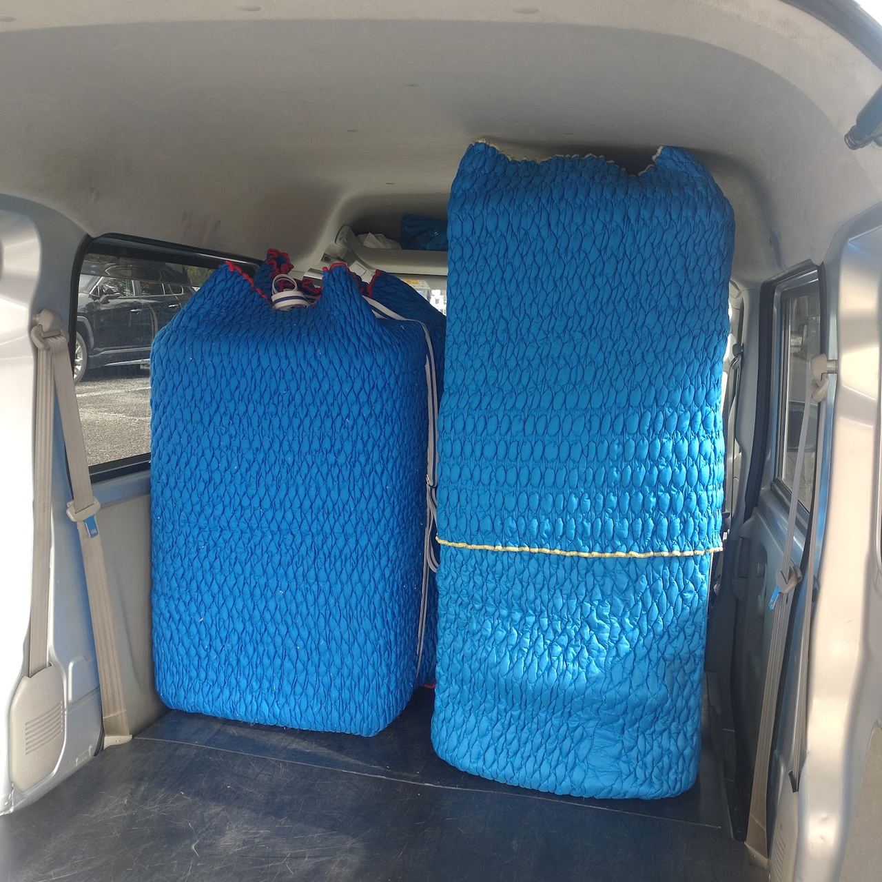 荷室に積まれた青い保護材で包んだ家具