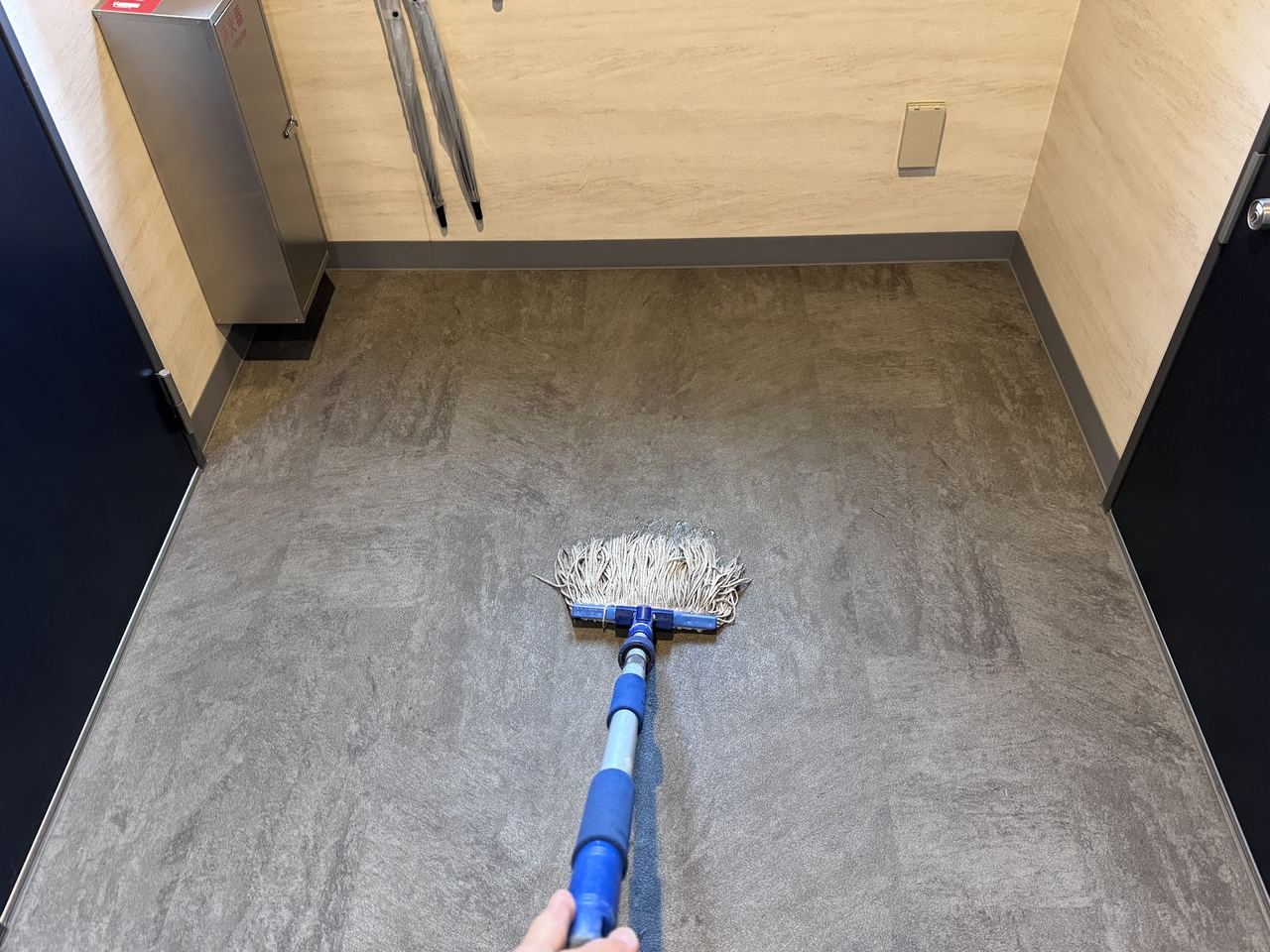 通路の床へ伸びる青い柄のモップ